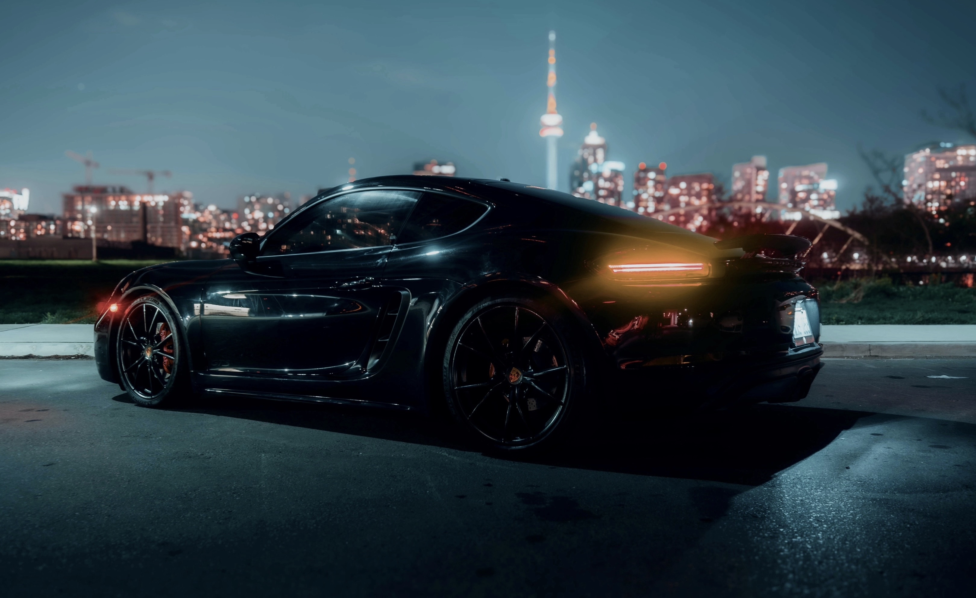 Black Porsche Cayman GTS with the CN Tower in the background